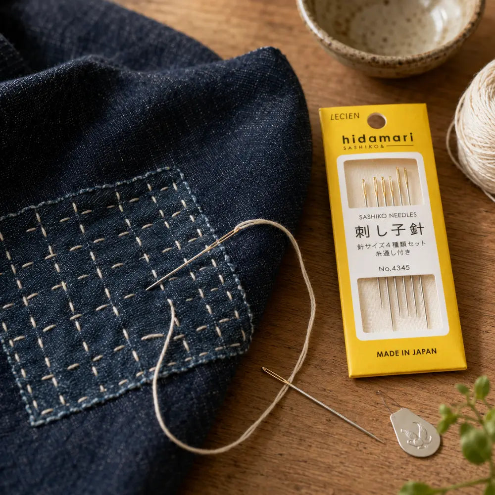 Hidamari sashiko needles by Lecien shown in a visible mending with denim, sashiko stitching, thread, and yellow package