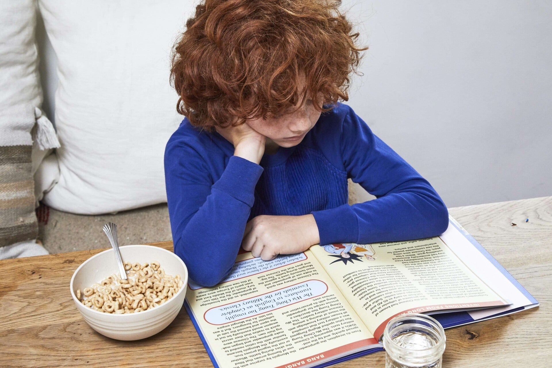 Child reading History Is Inventive book at a table in a home setting