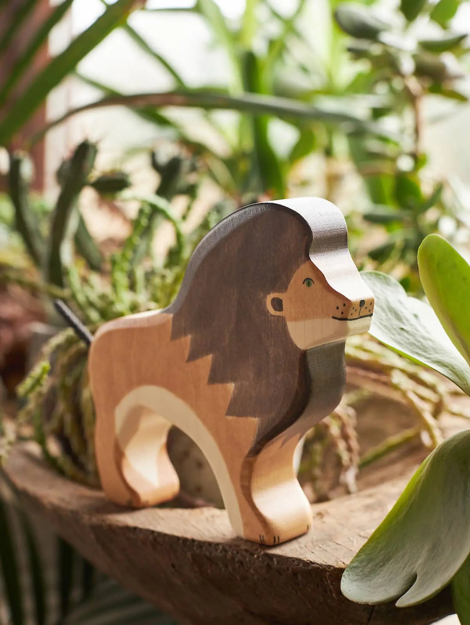 Wooden lion figurine on a natural surface with plants in the background