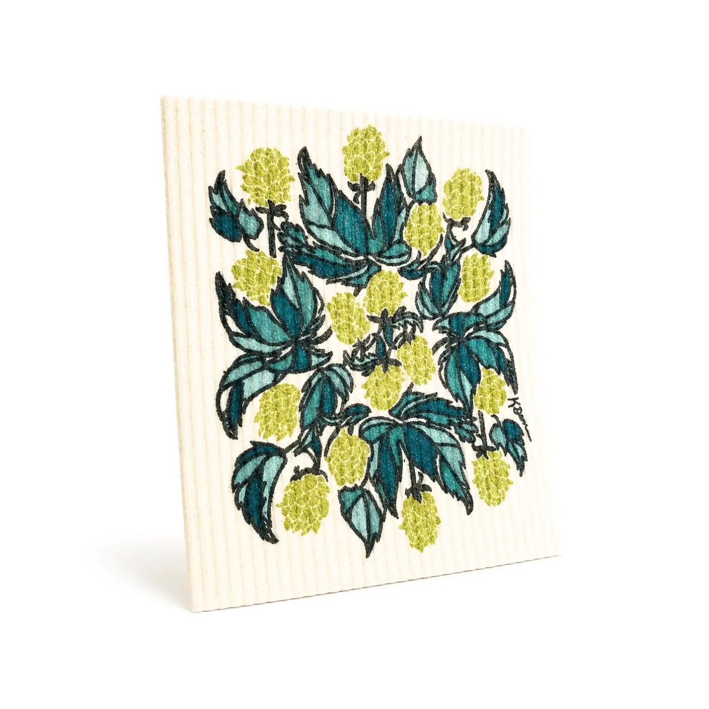 Hops Swedish dishcloth hanging beside a teal towel in a bright kitchen