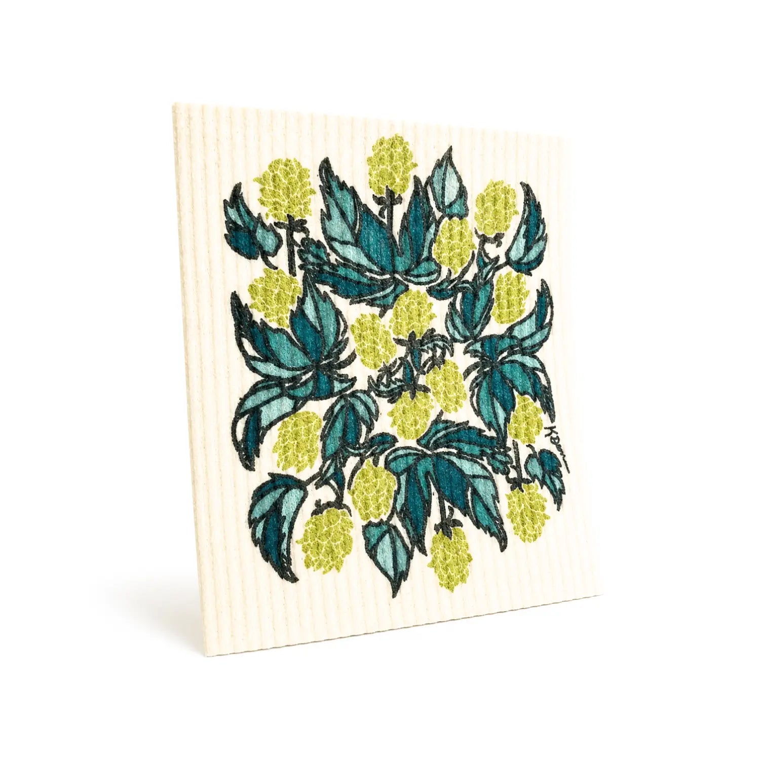 Hops Swedish dishcloth hanging beside a teal towel in a bright kitchen