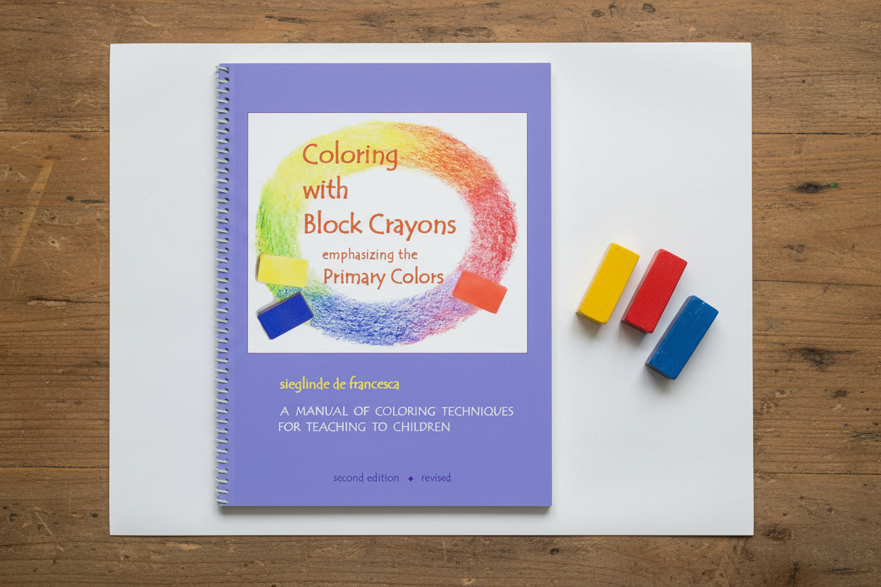 Book titled 'Coloring with Block Crayons' on a wooden surface with colorful block crayons.