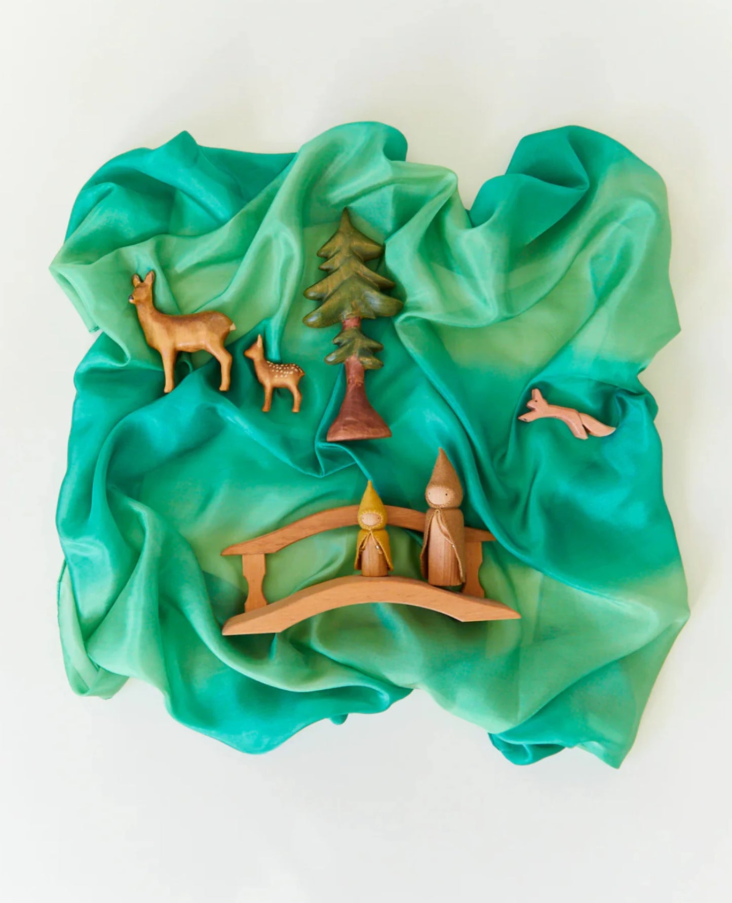 Earth playsilk in forest with wooden toys on top on a light background