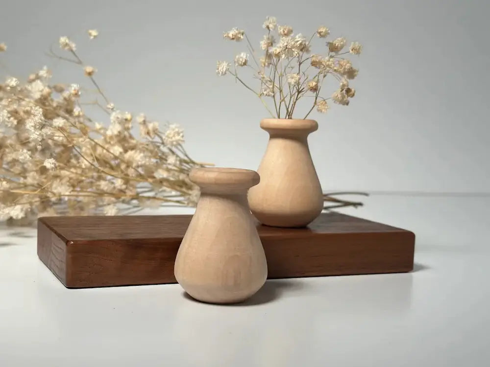 Two wooden vases with dried flowers on a gray background