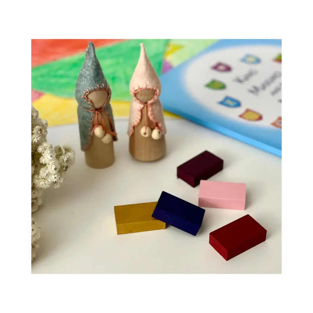 Colorful wooden peg doll gnomes with block crayons on a colorful background