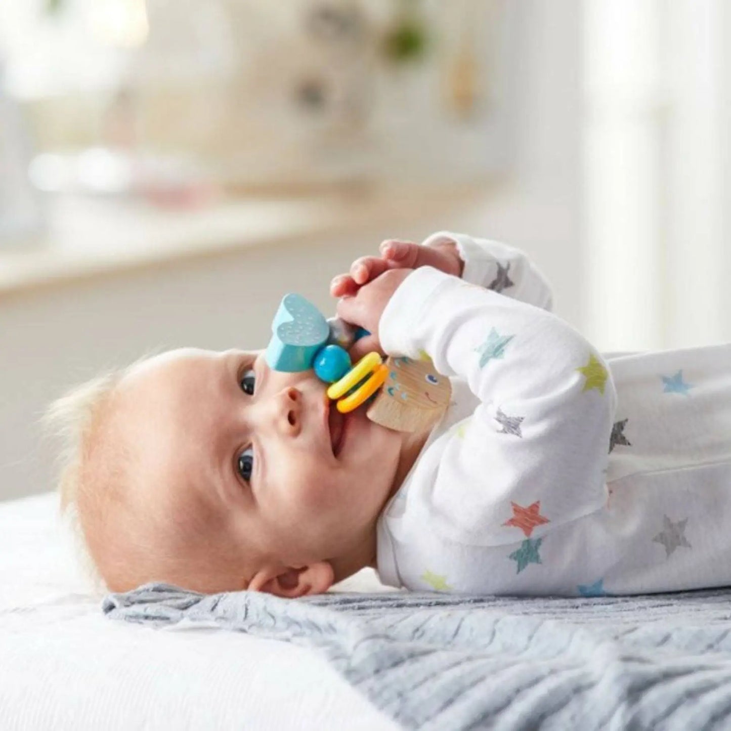 Baby playing with a colorful teething toy on a soft surface