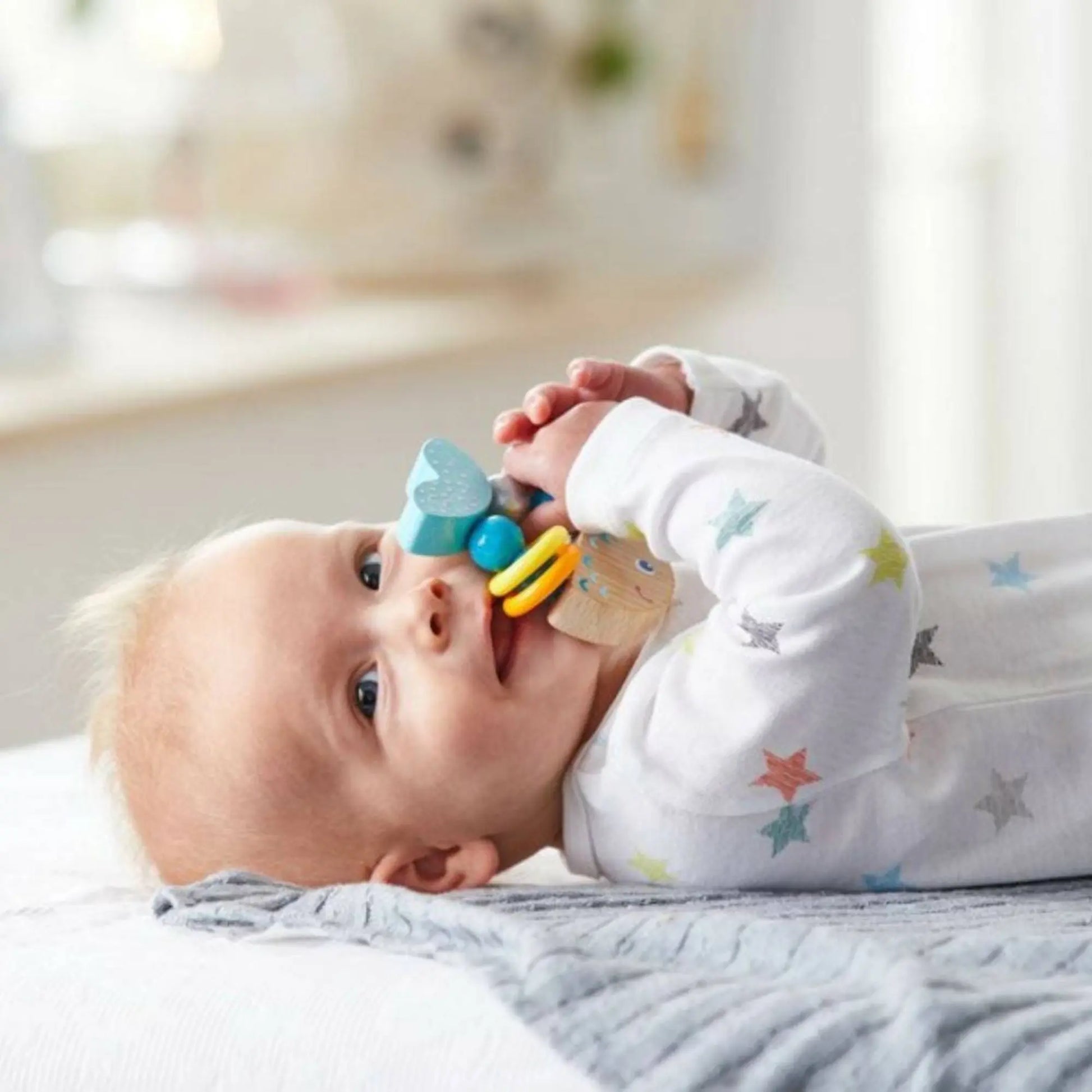Baby playing with a colorful teething toy on a soft surface