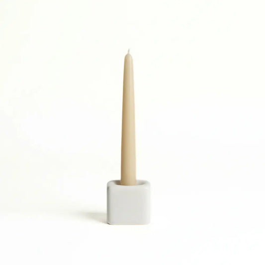 Beige candle in a white holder on a white background