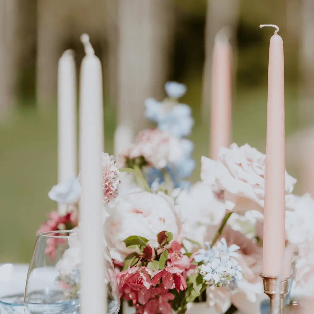 Table setting with ivory beeswax candles and flowers outdoors