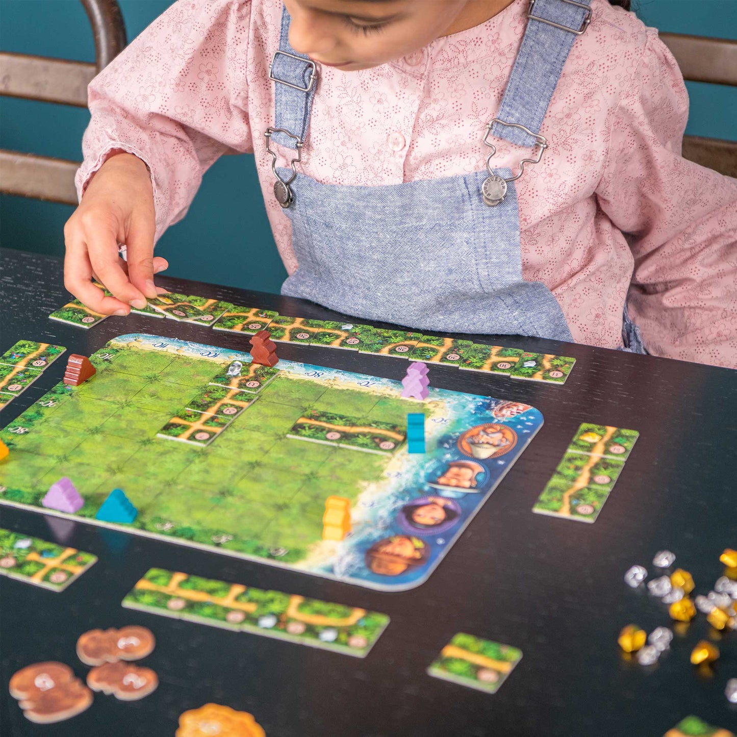 Child playing a board game with colorful pieces on a table