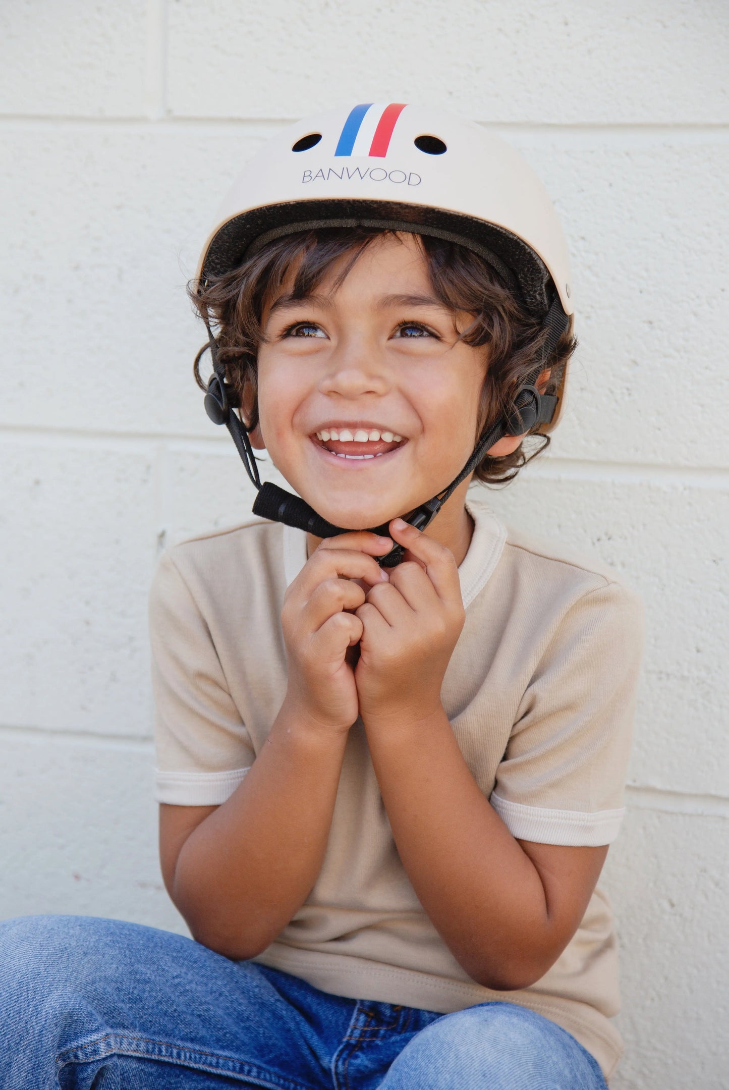 Child wearing a helmet with a visible brand logo against a white wall