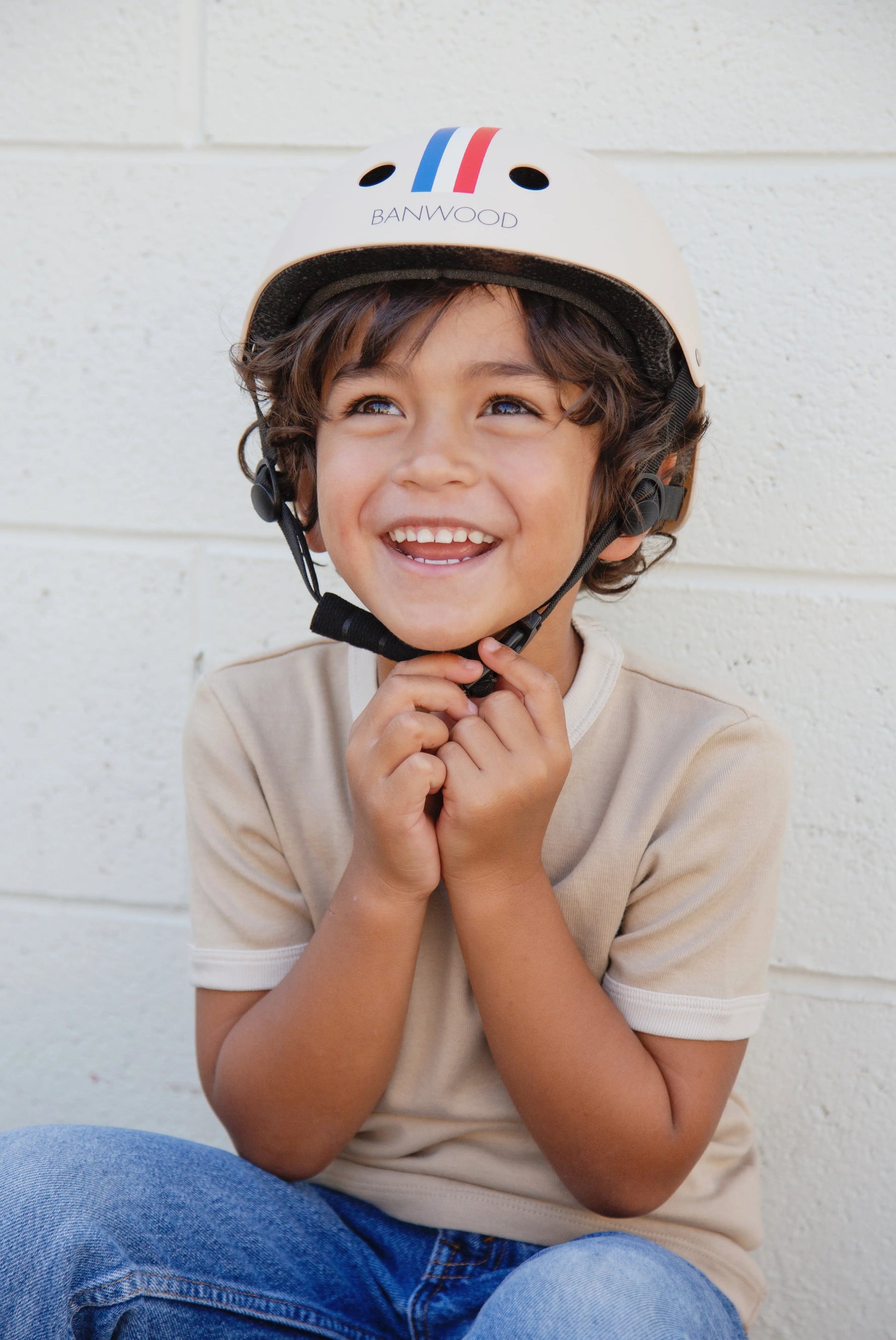 Child wearing a helmet with a visible brand logo against a white wall