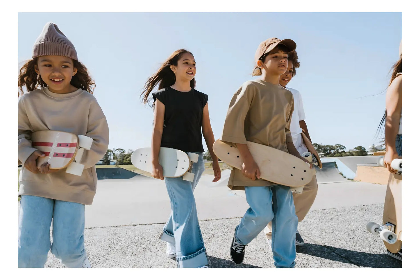 Three children with skateboards at a skate park.