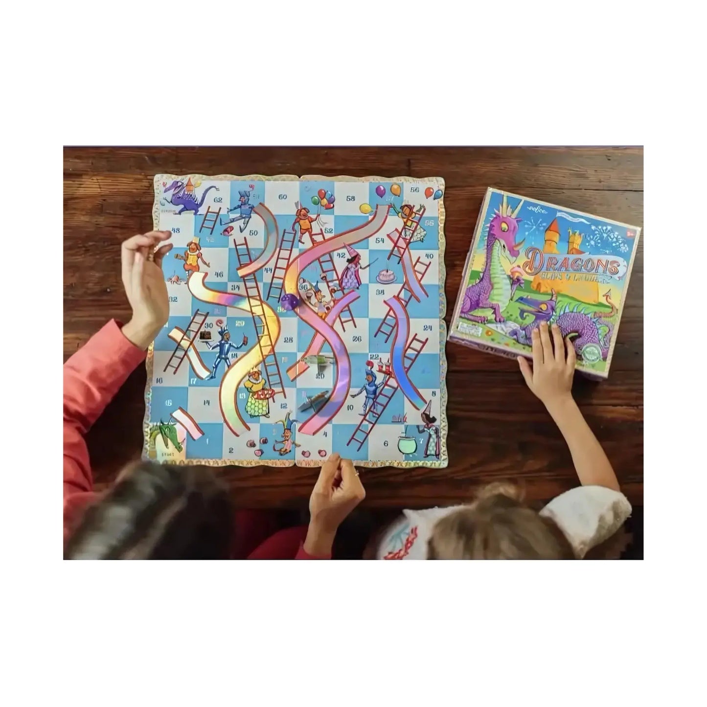 The Dragons slips and ladders board game on top of a wooden table with hands of two people
