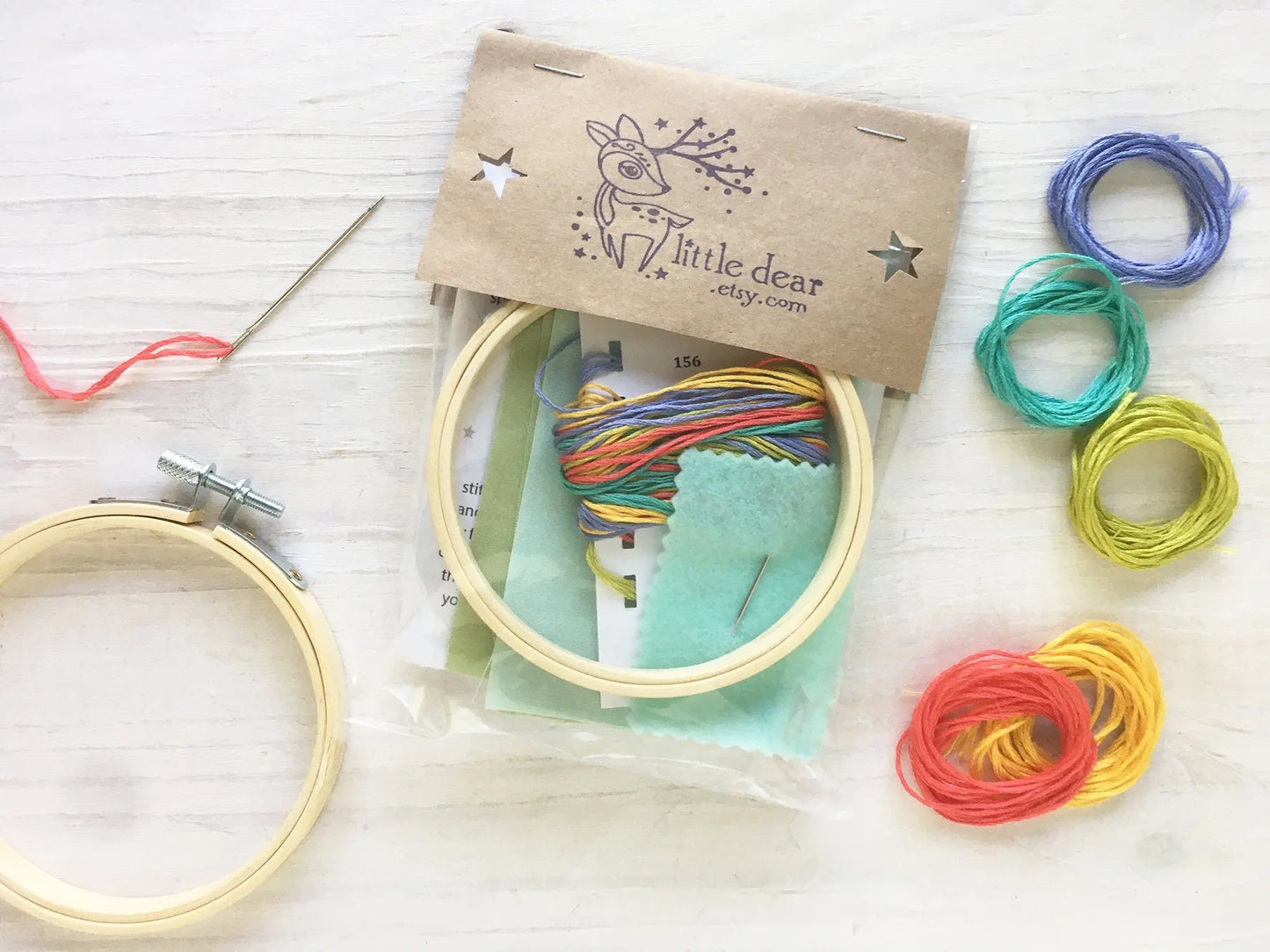 Children's embroidery kit with hoops, threads, and packaging on a white surface