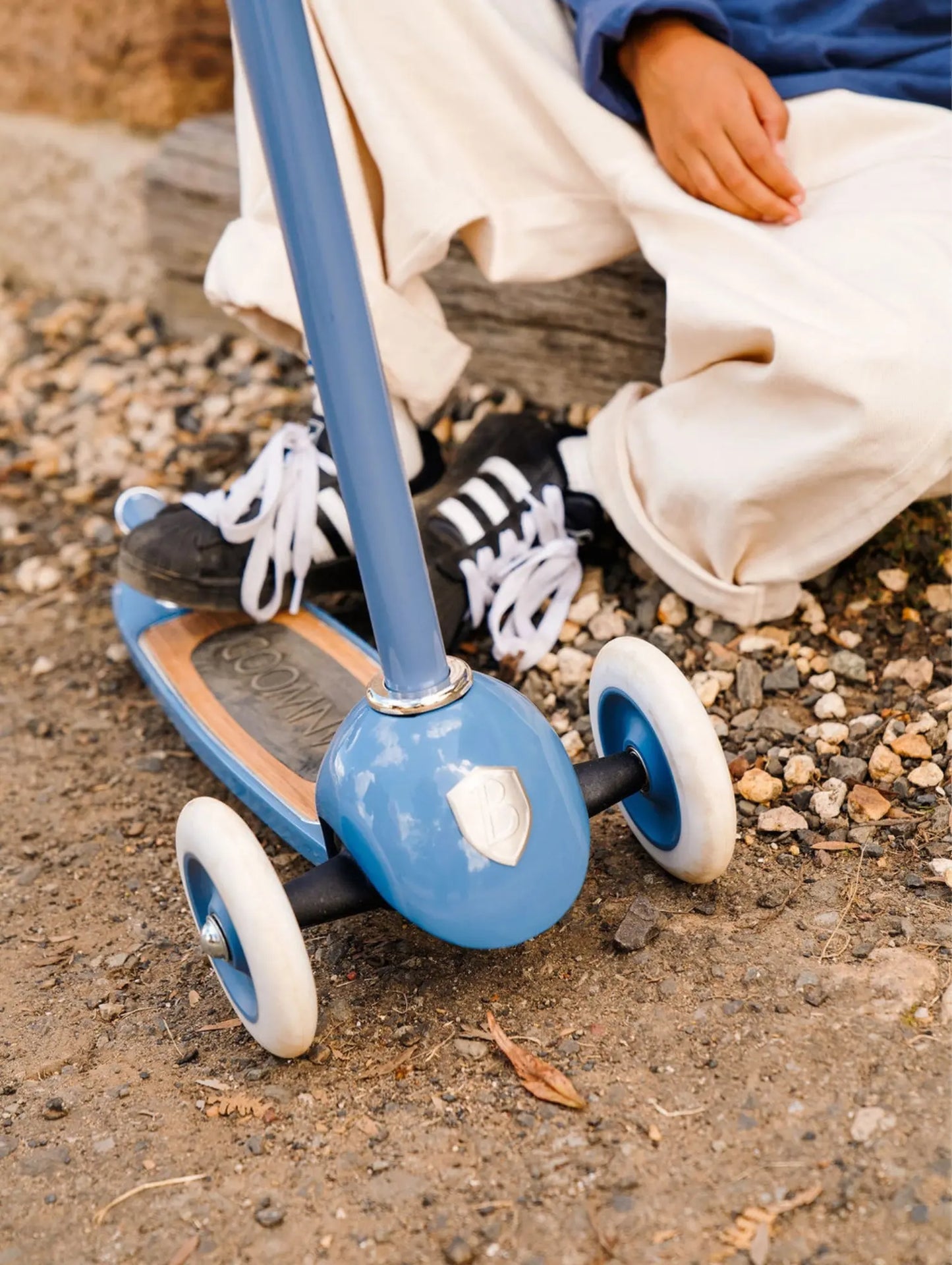 Blue scooter with white wheels on a rocky ground