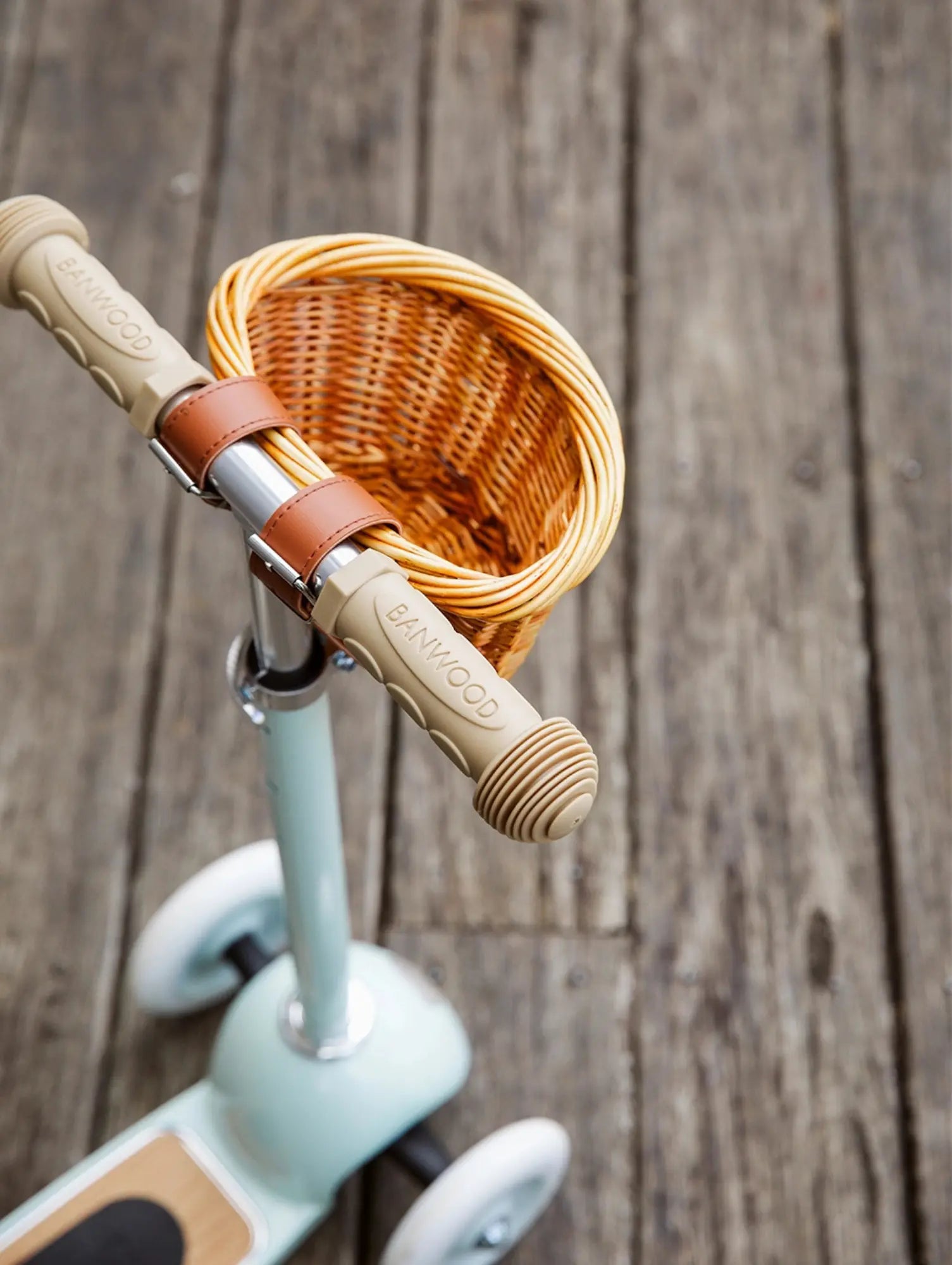 Children's scooter with woven basket on a wooden background