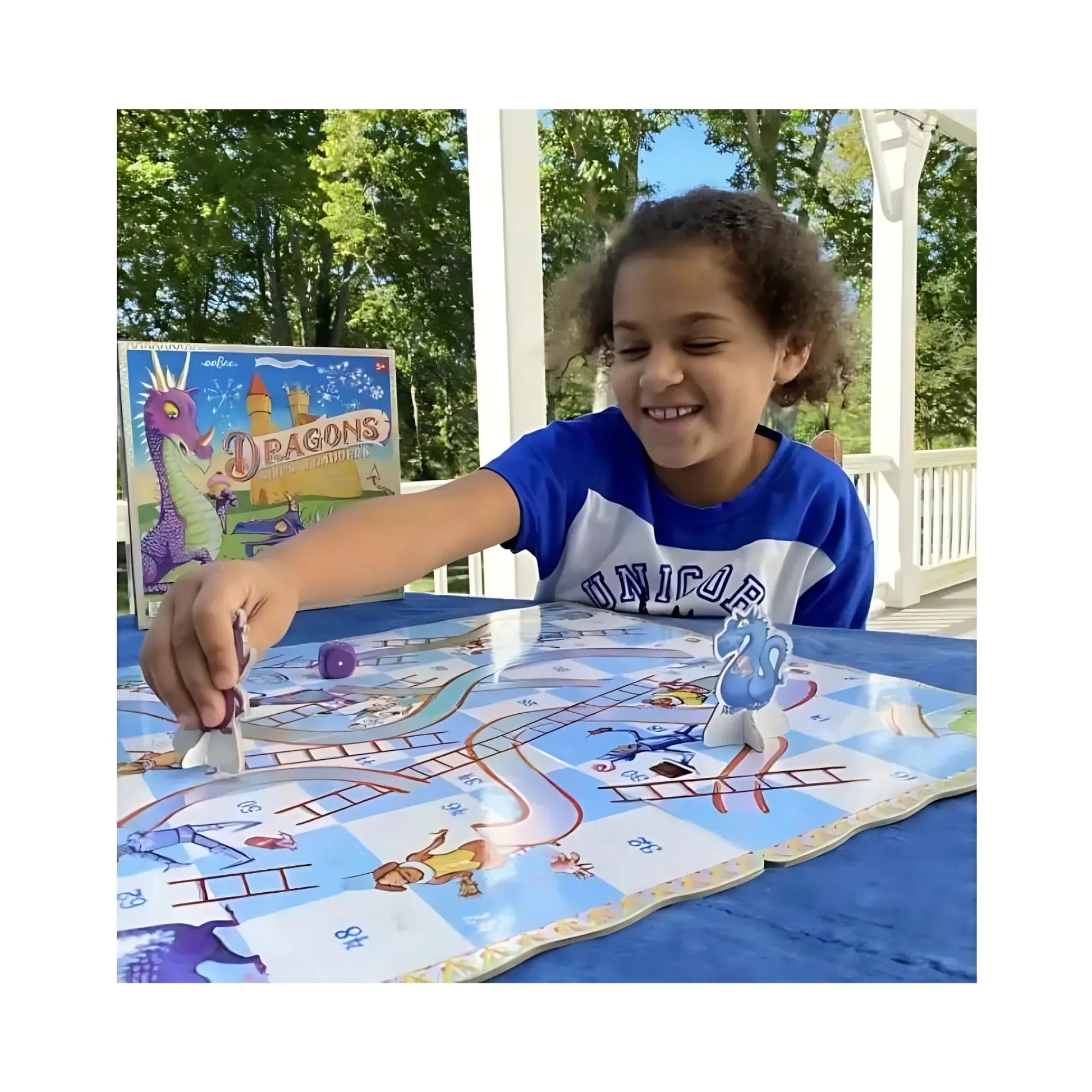 A child playing Dragons Slips and Ladders on a front porch on top of a blue table cloth