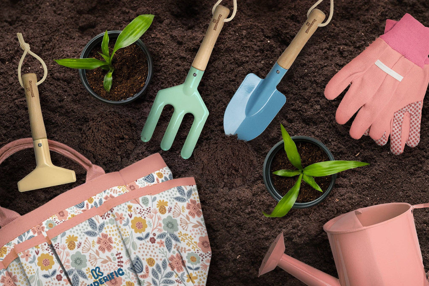 children’s gardening tools with gloves and tote bag arranged on soil