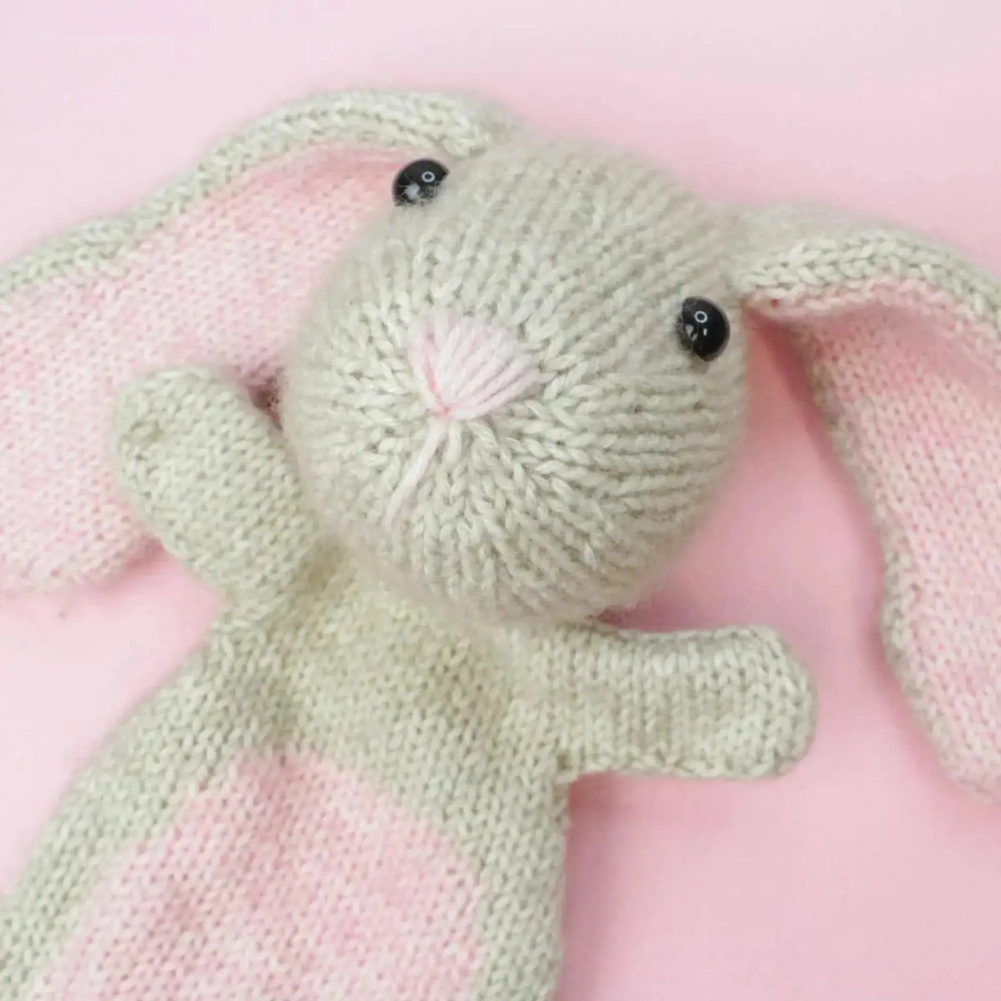 Close-up of handmade knitted bunny soft toy with pink ears