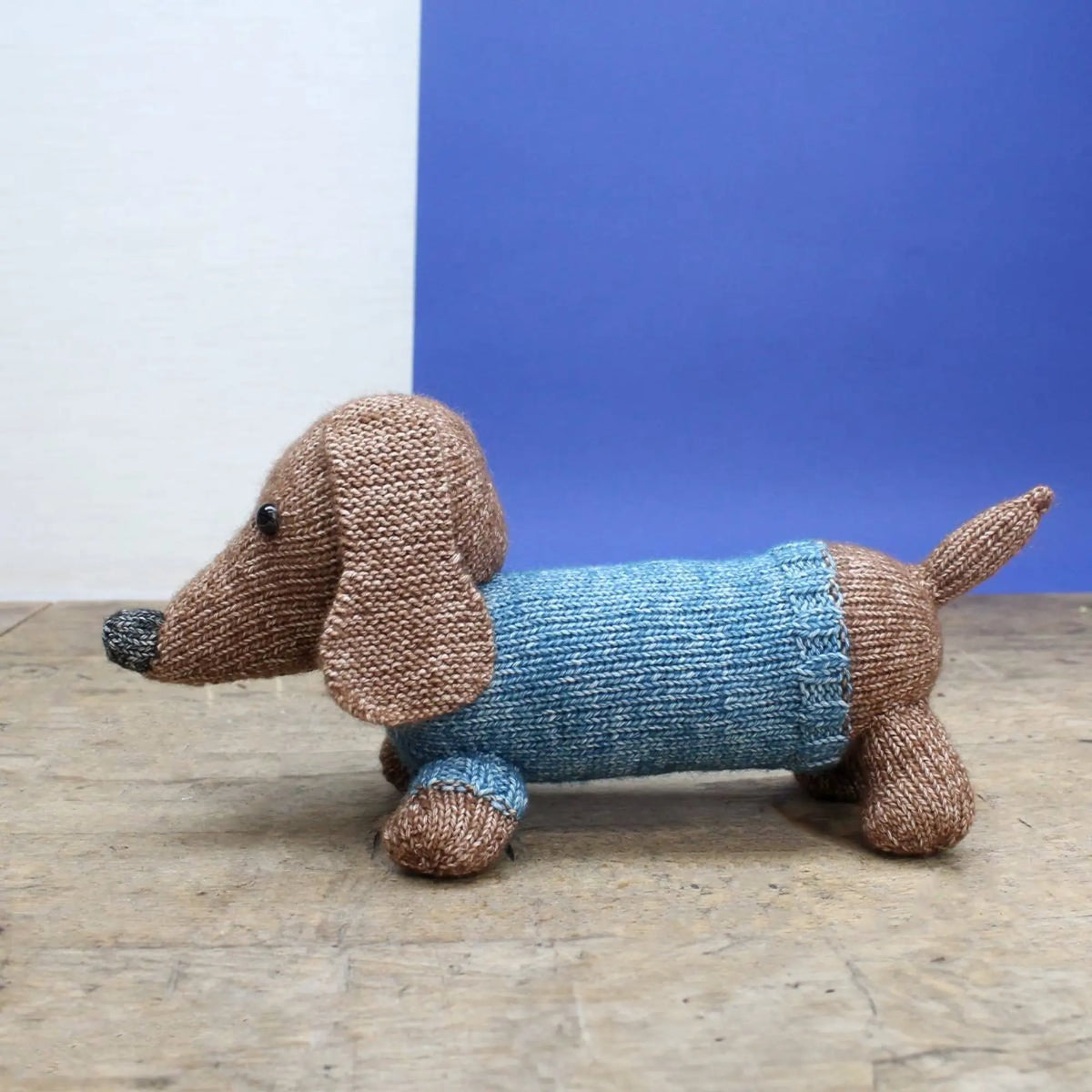 Side view of knitted dachshund stuffed animal with blue body