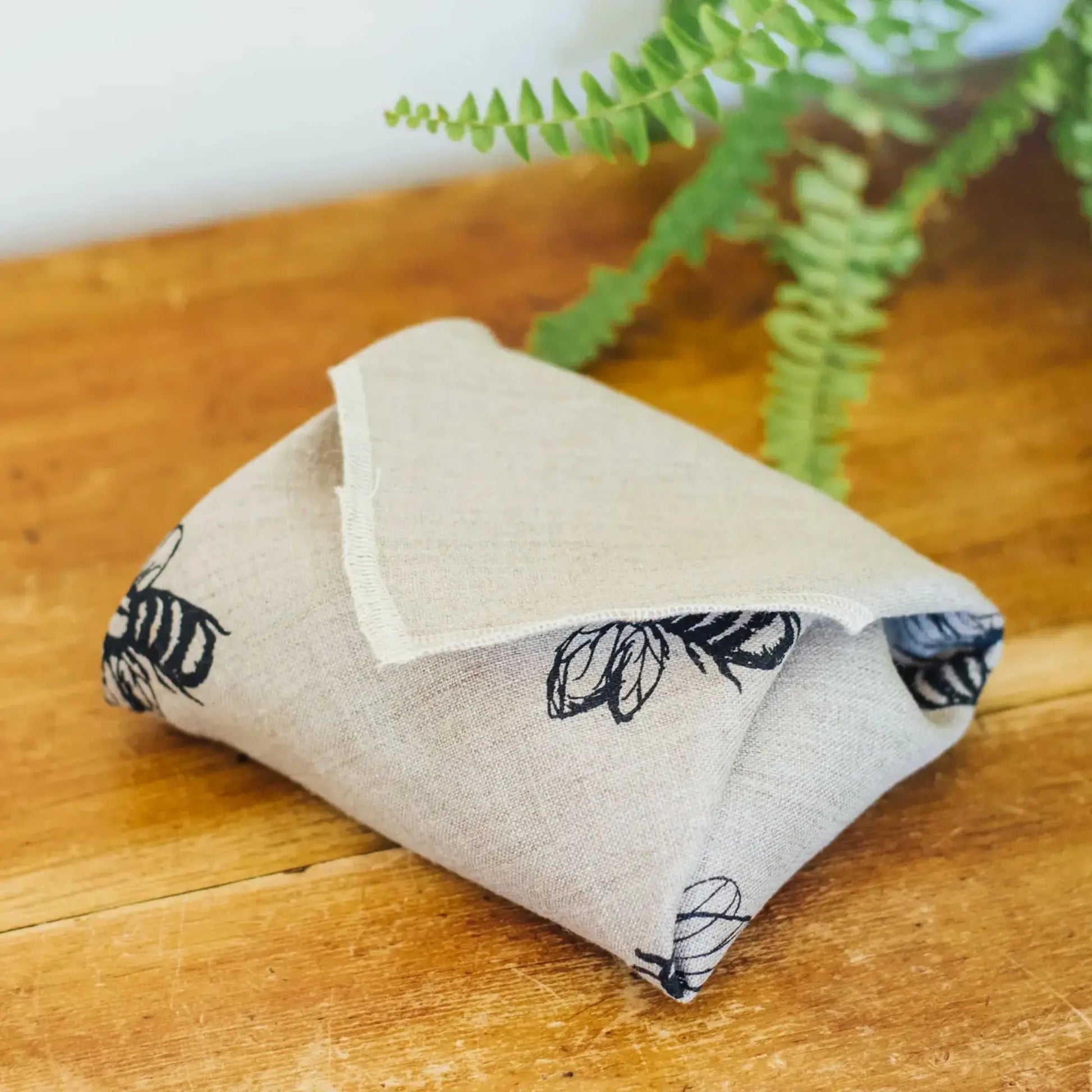 Folded fabric sandwich wrap with bumble bee pattern on a wooden surface