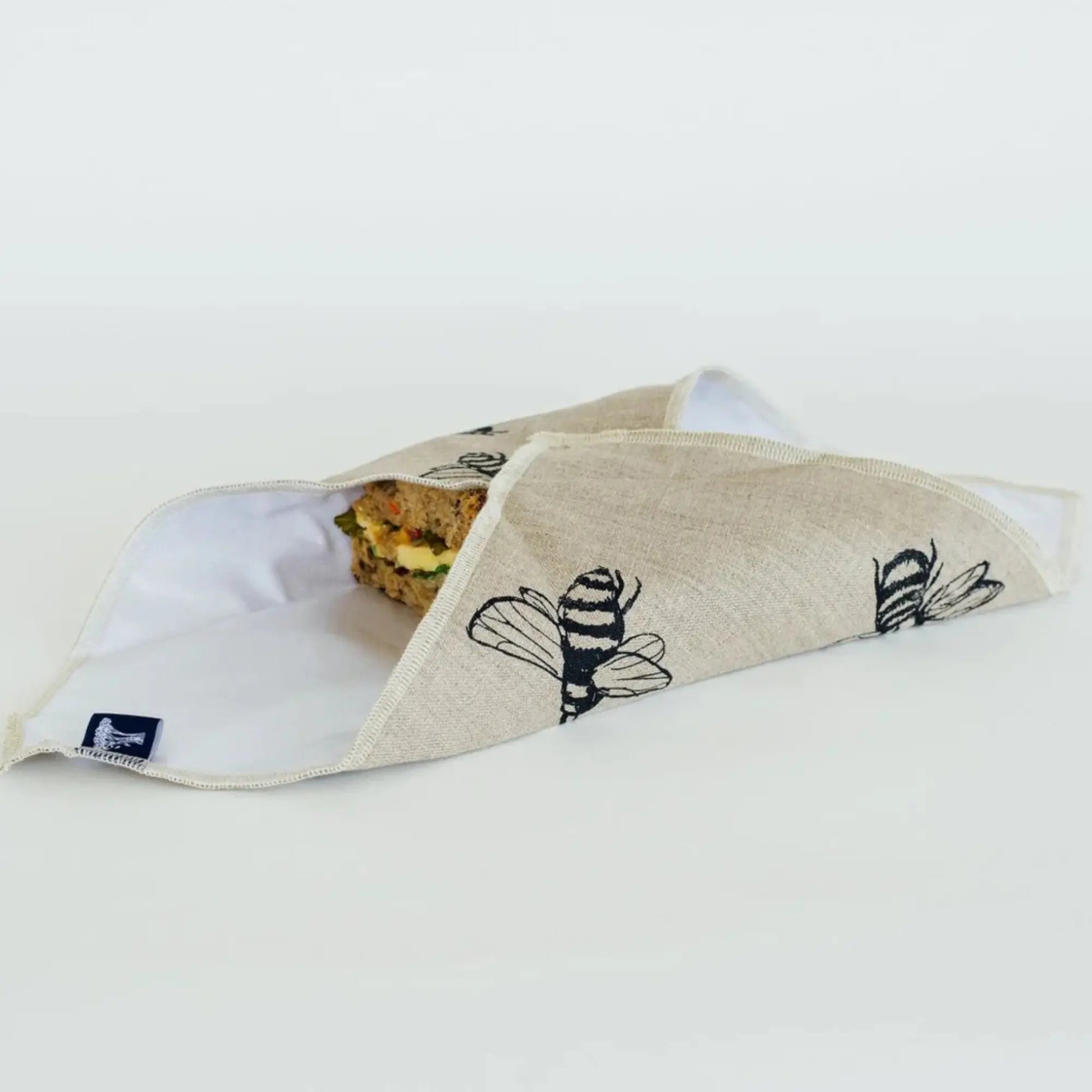 Folded linen sandwich wrap with bee pattern on a white surface