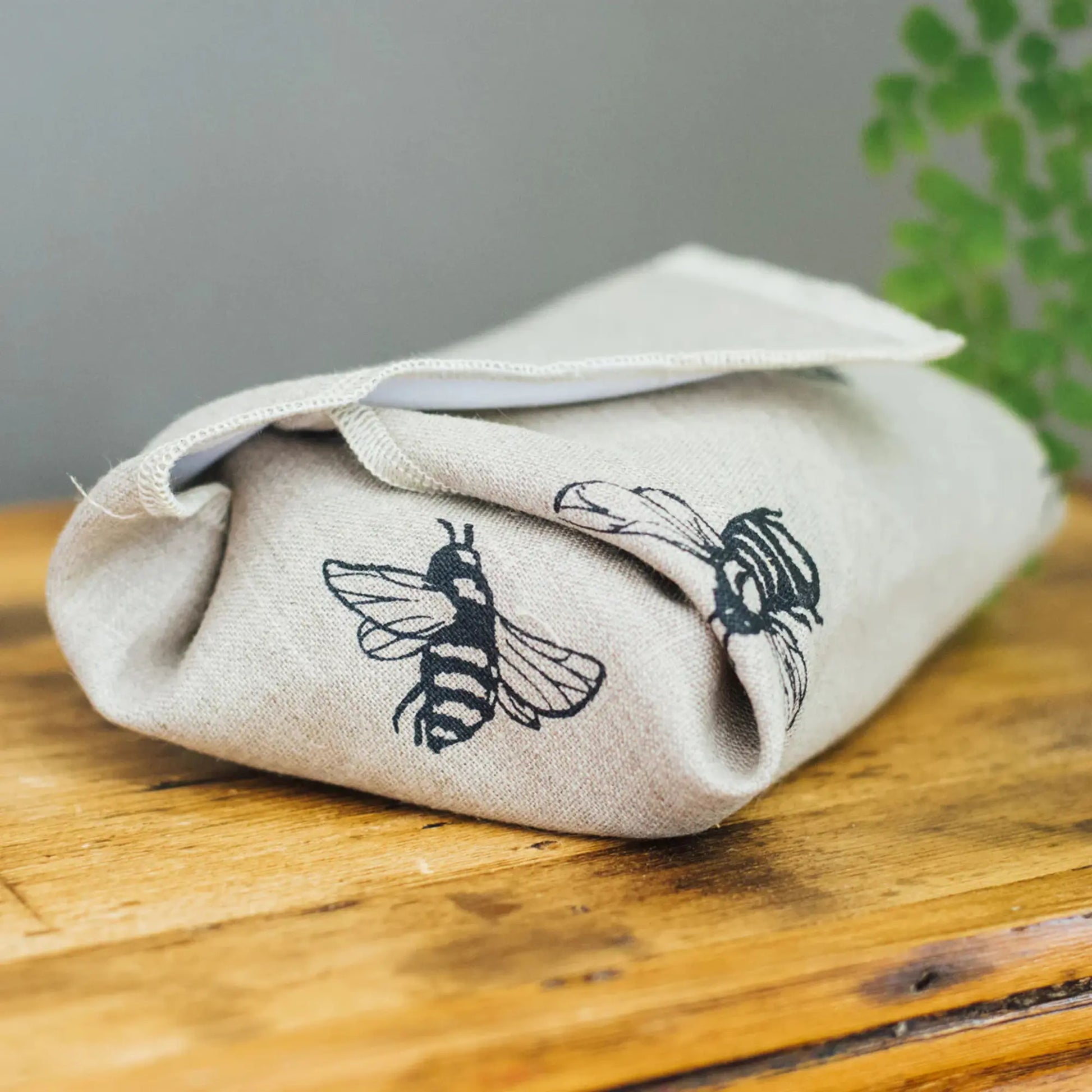 Sandwich wrap wrapped around a sandwich with bee designs on a wooden surface