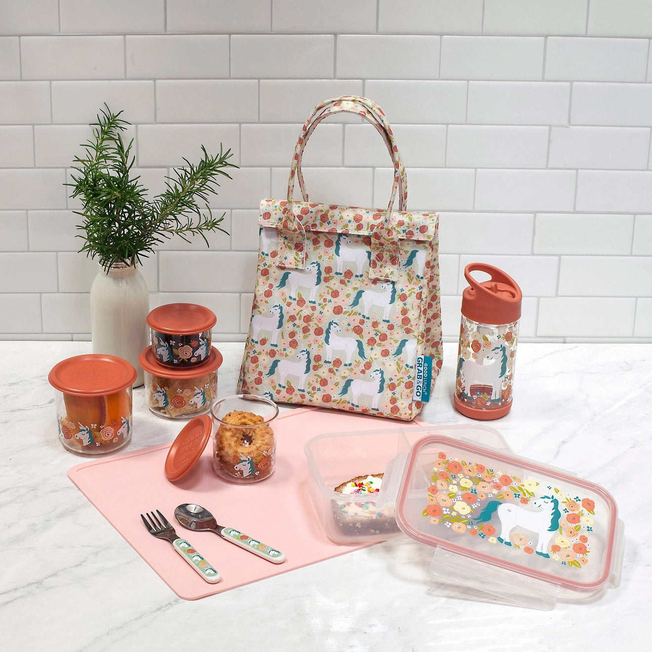 Assorted kitchen items including a floral-patterned lunch bag, lunch bag containers, and utensils on a white surface