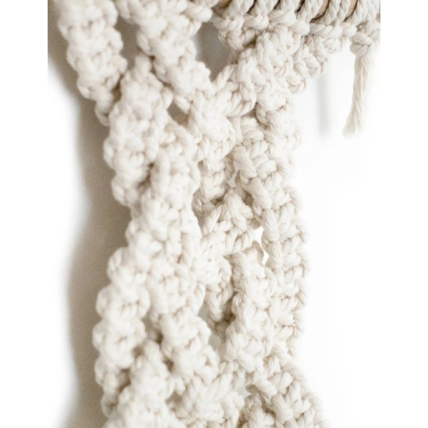 Close-up of a textured white macrame cord with a braided pattern on a light background