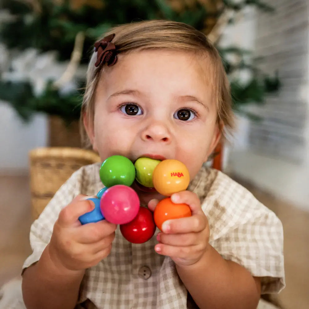 Child holding and playing with a colorful HABA toy