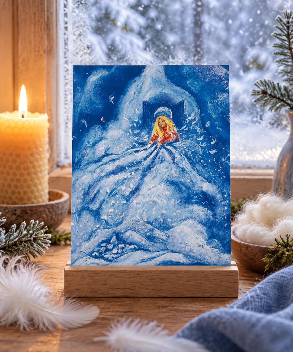 Marjan van Zeyl Mother Hulda fairy tale postcard displayed in a wooden holder on a winter story table beside a snowy window, with a beeswax candle, white feathers, wool, and evergreen sprigs.
