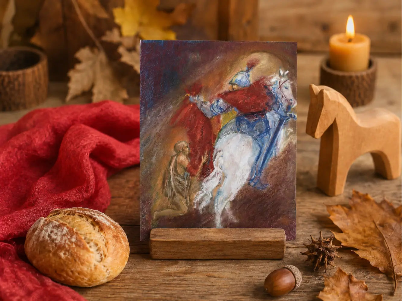 Martin Gives His Coat postcard by Marjan van Zeyl displayed on a rustic table with red silk