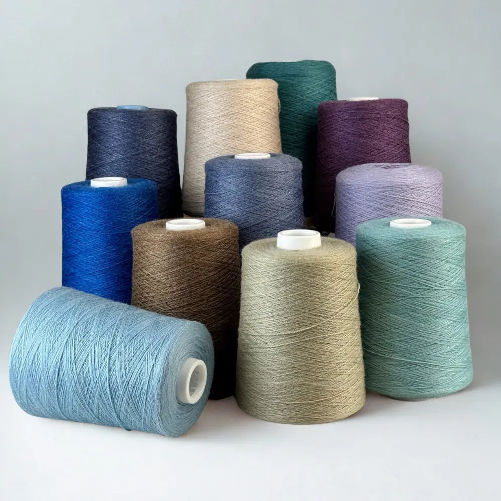 Assorted spools of yarn in various colors on a light gray background