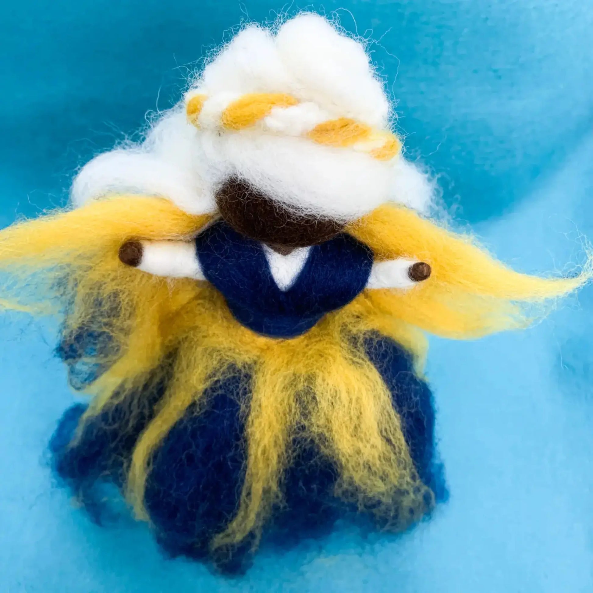 Handmade fairy with white hair, yellow wings, and blue clothing on a blue background
