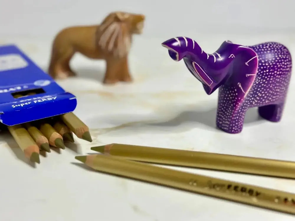 Colorful animal figurines and gold colored pencils on a white surface