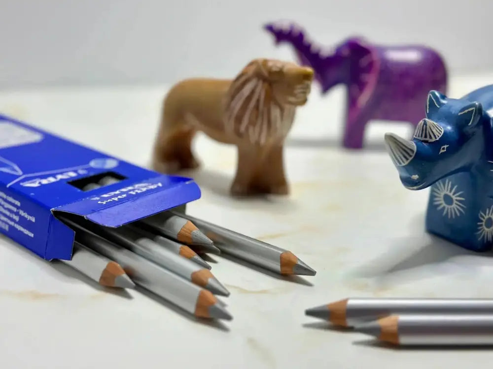 Silver colored pencils with a blue box and decorative animal figurines on a light surface