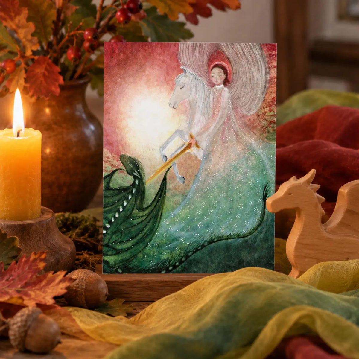 Michaelmas postcard displayed on a seasonal table with autumn silk, beeswax candle, acorns, and a simple wooden dragon