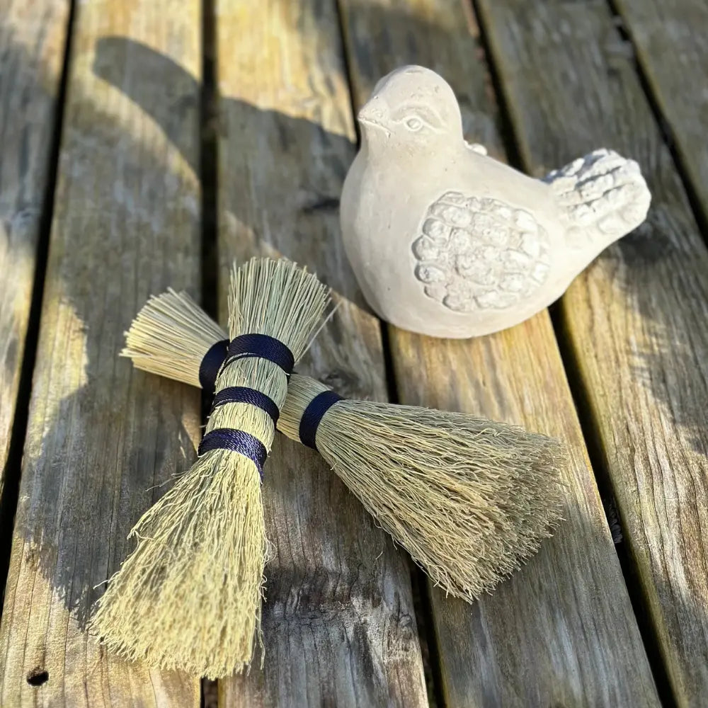 Decorative broom and stone bird on a wooden surface