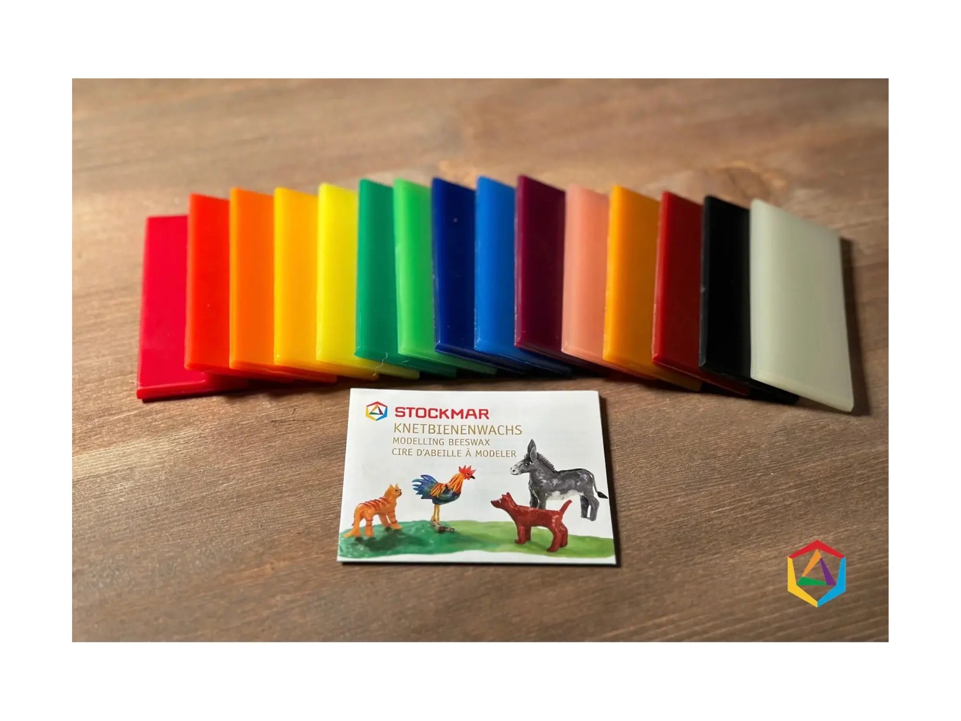 Modeling beeswax in assorted colors fanned out on a wooden table showing full color range and natural wax texture