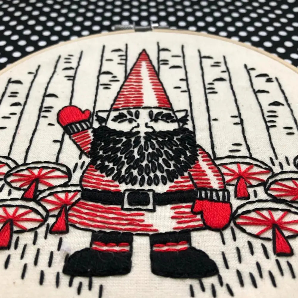 Close-up of gnome embroidery with red mushrooms and black beard details