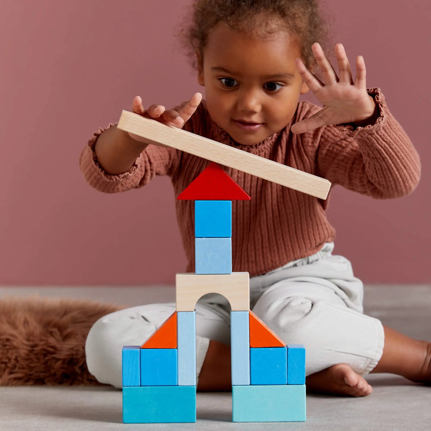 Child playing with wooden blocks on a plain background