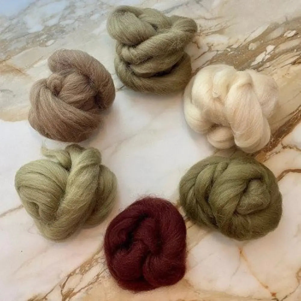 Set of six skeins of combed wool top in various earth tones on marble background