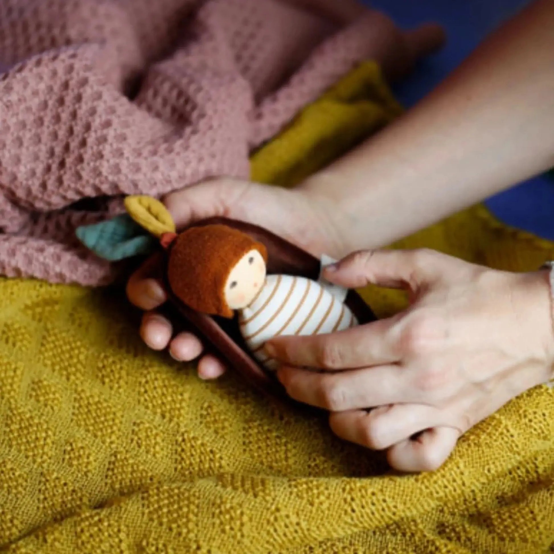 baby holding organic nanchen rattle doll showing size and soft fabric