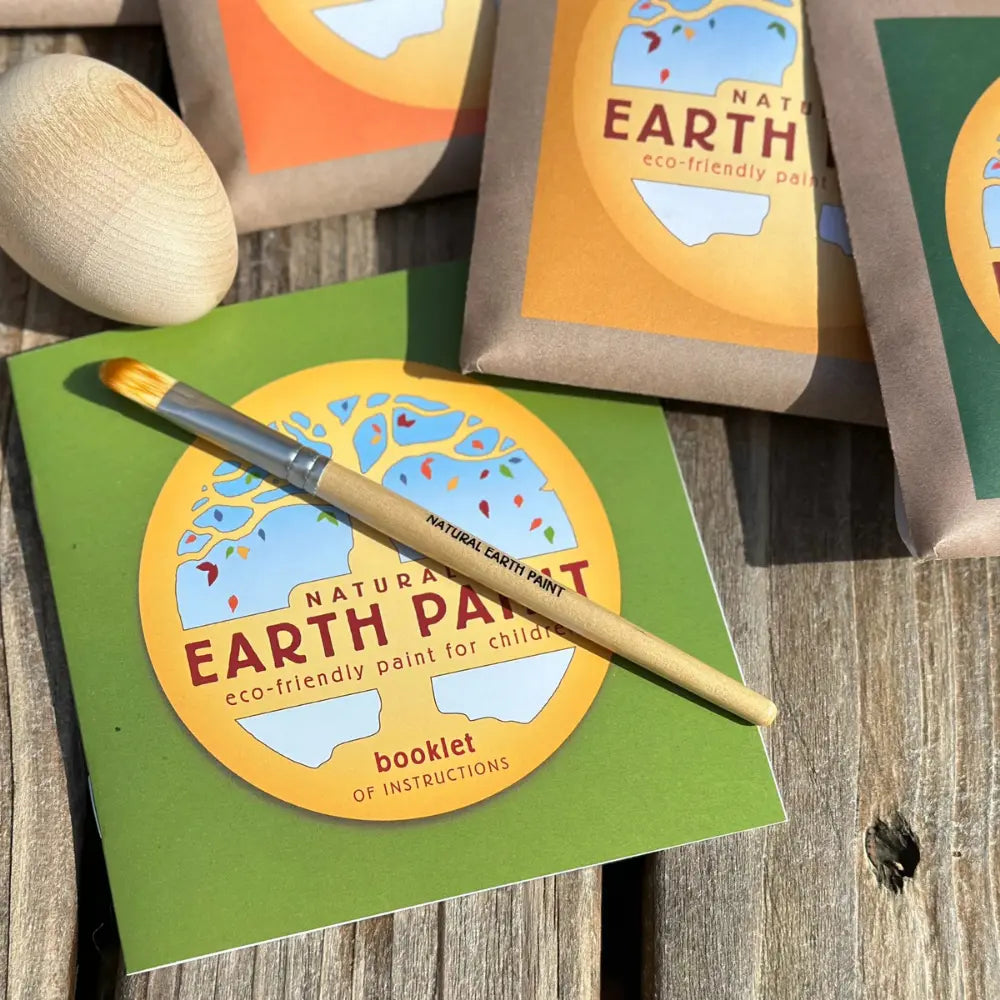 Earth Paint packaging with a brush on a wooden surface