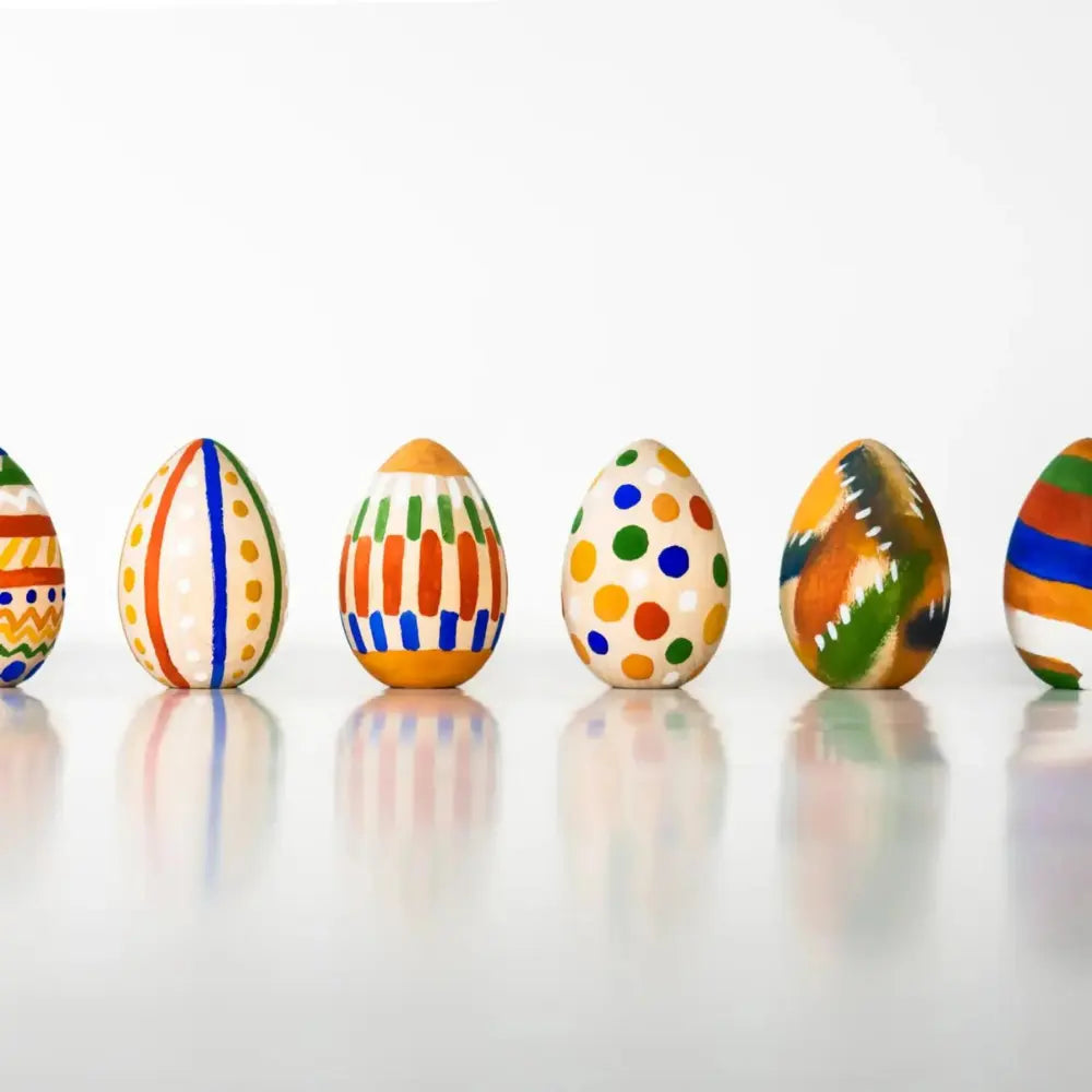 Colorful patterned eggs on a reflective surface with a white background