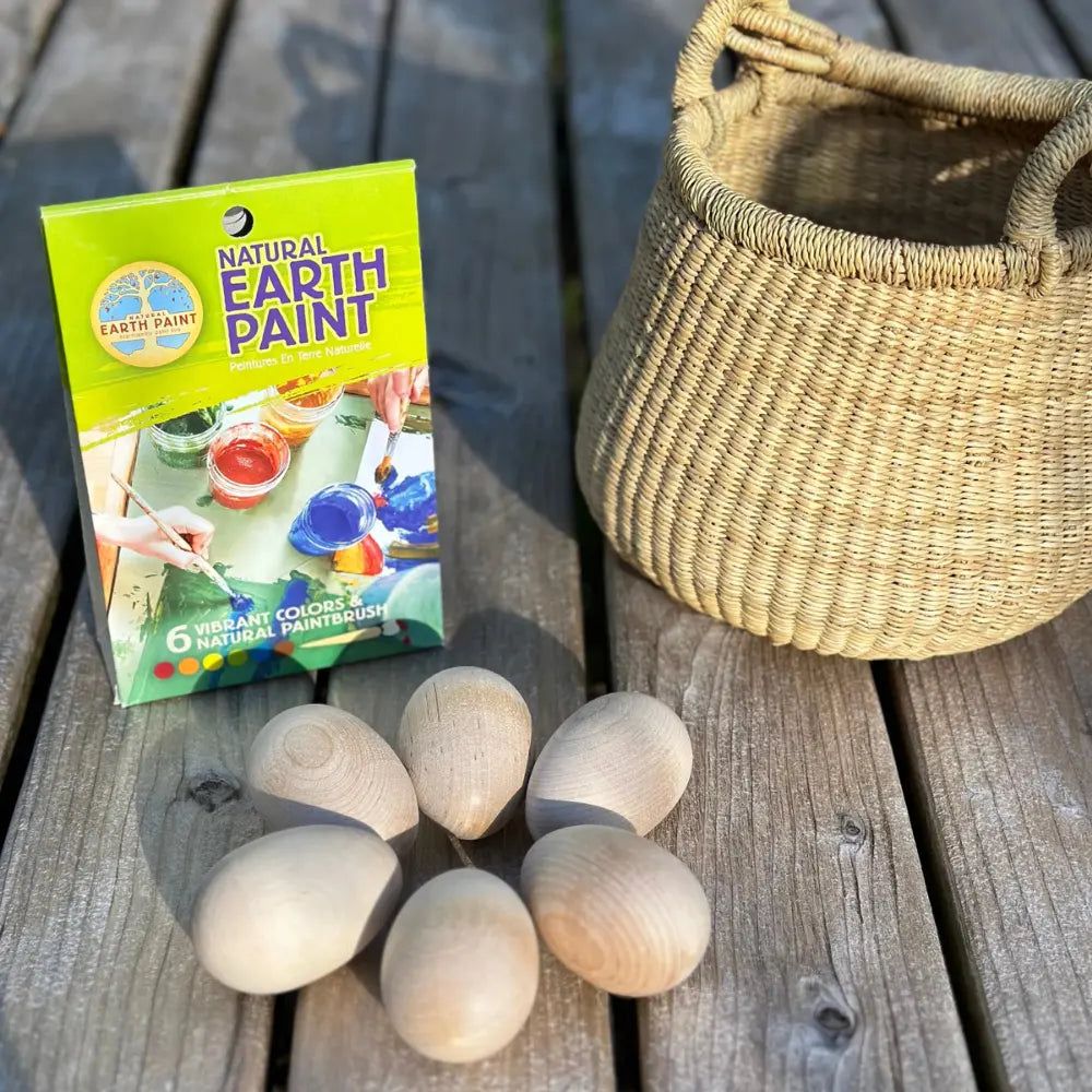 Box of Natural Earth Paint with wooden eggs and a woven basket on a wooden surface