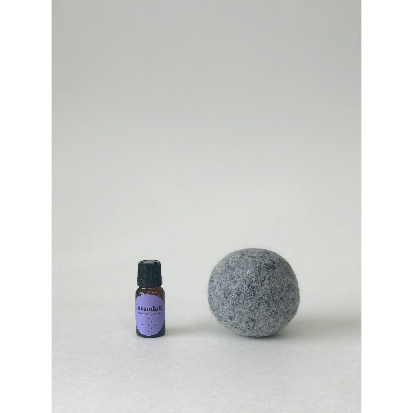 gray wool dryer ball next to a small bottle of lavendula essential oil
