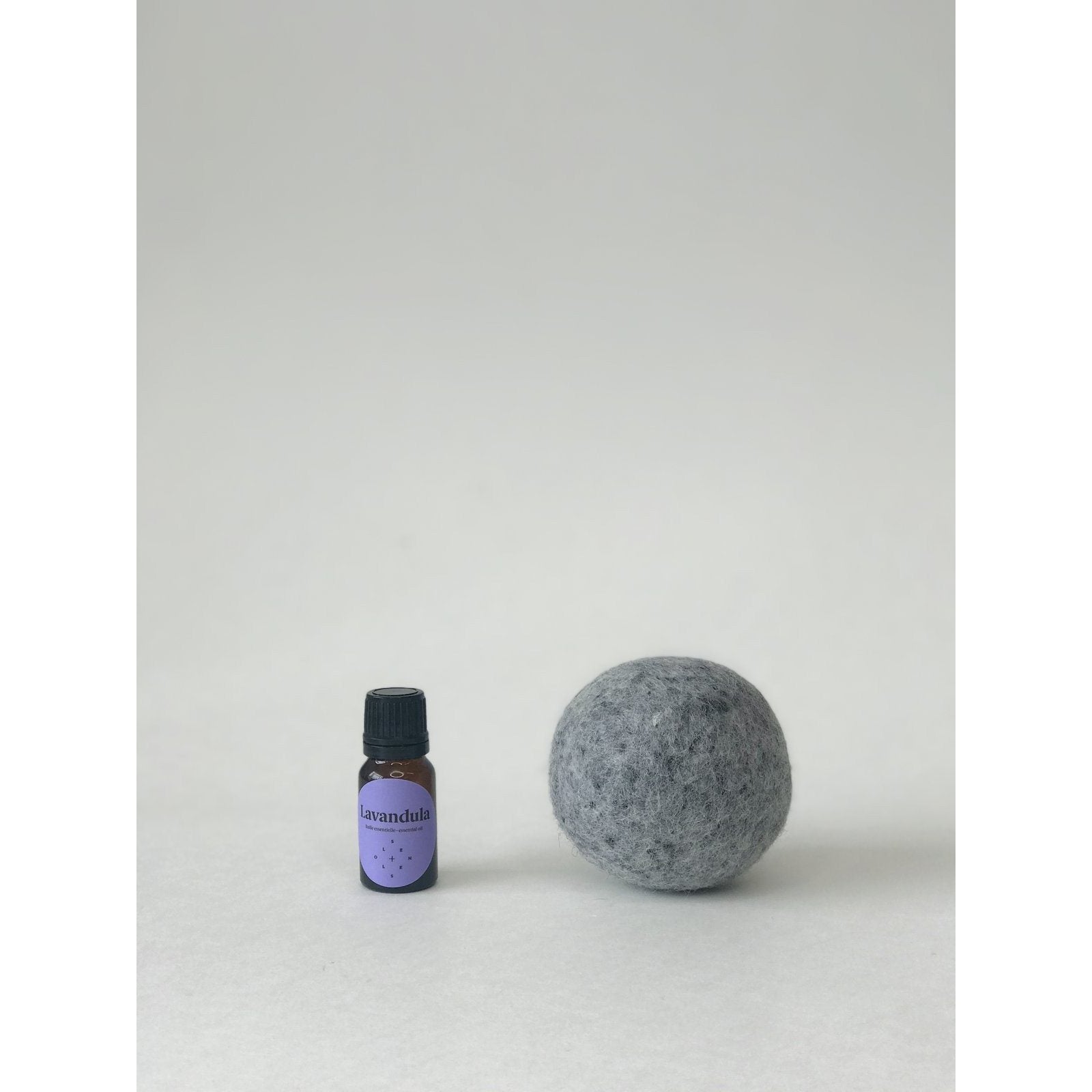gray wool dryer ball next to a small bottle of lavendula essential oil