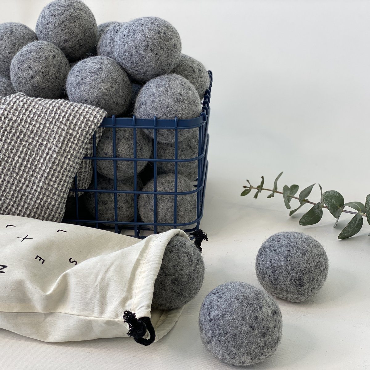 Gray wool dryer balls in metal basket with eucalyptus
